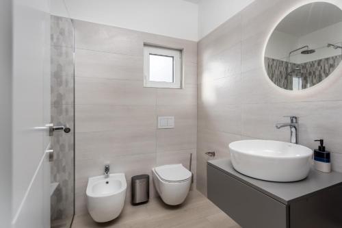 a bathroom with a sink and a toilet and a mirror at Luxury villa BOREAS with private pool and sea view in Šmrika