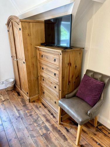 a tv sitting on top of a wooden dresser with a chair at Fairhaven Stay in Betws-y-coed