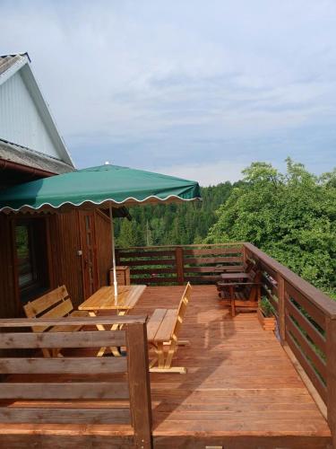 a wooden deck with a table and an umbrella at Будиночок для щастя in Yaremche