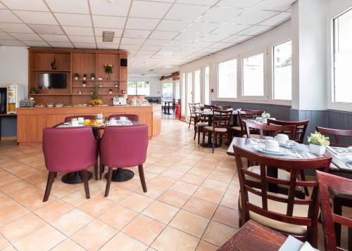 a restaurant with tables and chairs and a kitchen at HOTEL l'EAUBONNE in Eaubonne