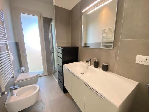 a bathroom with a sink and a toilet and a mirror at Vittoria Apartament in Tirrenia