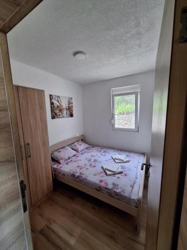 a small bedroom with a bed and a window at Apartmani Seaview in Sutomore