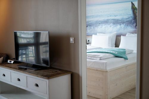 a bedroom with a bed with a television on a table at Beach Apartments Heiligenhafen in Heiligenhafen
