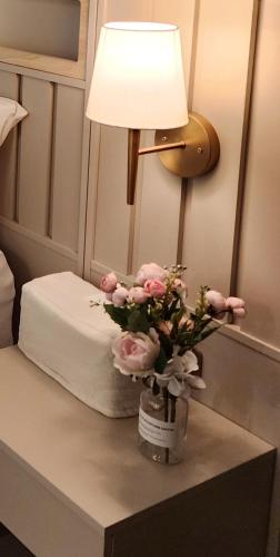 a table with a lamp and a vase of pink flowers at Lucy Stay in Seoul