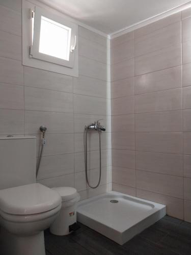 a bathroom with a shower and a toilet and a window at Sea balcony in Marathokampos