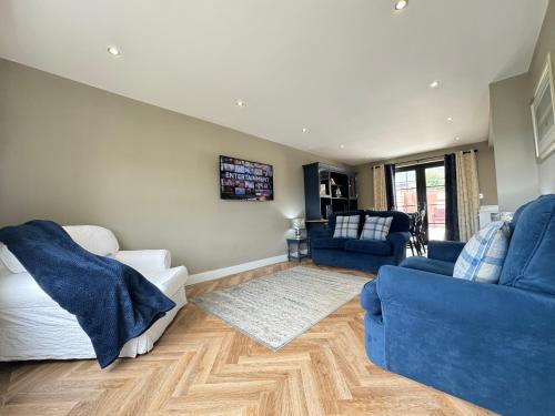 a living room with two blue couches and a tv at Victoria Cottage, Cullercoats in Cullercoats