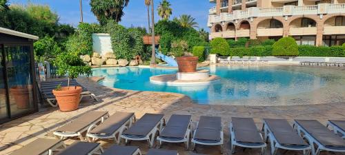 une piscine avec des chaises longues devant un immeuble dans l'établissement Appartement spacieux climatisé piscines, à Cannes