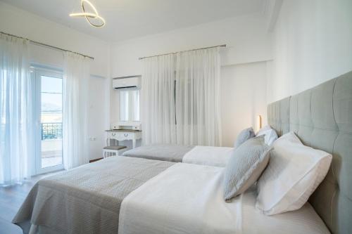 a white bedroom with two beds and a window at Calliope Luxury Apartment in Sitia