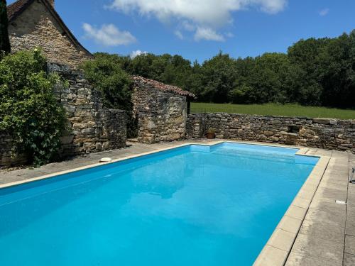 - une piscine en face d'un mur en pierre dans l'établissement Petit Loulet, à Puylagarde