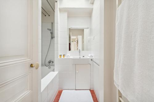 une salle de bain blanche avec un lavabo et une douche dans l'établissement Veeve - The Bibliophile’s Haven, à Paris