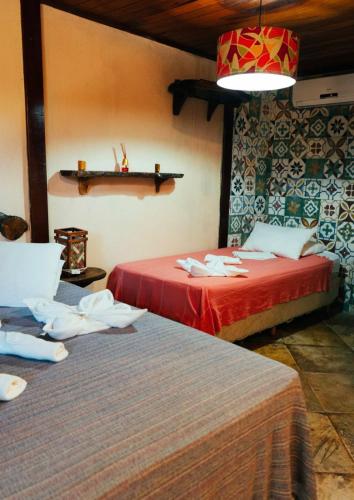 two beds in a room with red sheets at Kitecabana Pousada in Cumbuco