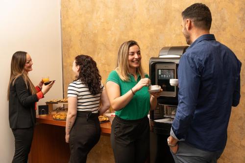 a group of people standing around a coffee machine at Novotel Roma Est in Rome