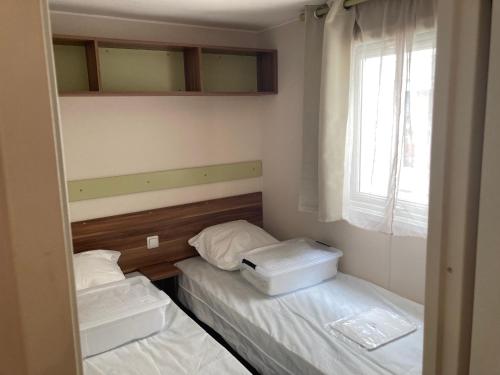 deux lits dans une petite pièce avec une fenêtre dans l'établissement mobil home L escale, à Meschers-sur-Gironde