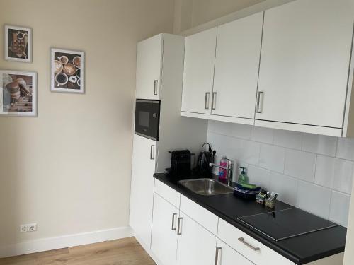 a kitchen with white cabinets and a sink at Aristoteles Apartments in Scheveningen