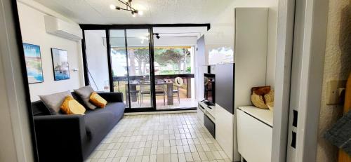 un salon avec un canapé et une grande fenêtre dans l'établissement Un Jardin proche de la Plage et commerces, au Grau-du-Roi