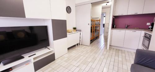 une cuisine avec une grande télévision à écran plat sur un mur dans l'établissement Un Jardin proche de la Plage et commerces, au Grau-du-Roi