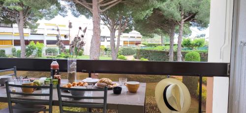 - une table avec de la nourriture sur un balcon arboré dans l'établissement Un Jardin proche de la Plage et commerces, au Grau-du-Roi