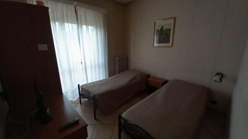 a small room with two beds and a window at La Terrazza in Cherasco