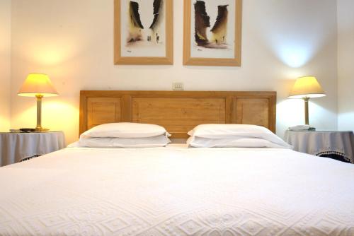 a large white bed with two pillows on it at Hotel Locanda Cairoli in Rome