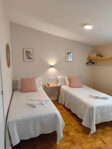 two beds in a room with white walls and wooden floors at Villa Galicia (Padrón) in Padrón