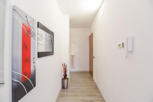 a hallway with white walls with paintings on the walls at Vallategna Apartment Lake Como and Mountains in Asso