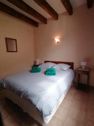 a bedroom with a bed with two green towels on it at Gîte Monplaisir in Gère-Belesten
