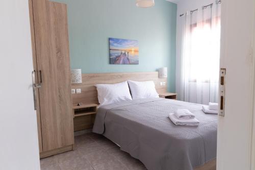 a bedroom with a white bed with a wooden headboard at Sunrise Vergia Apartments in Vergia