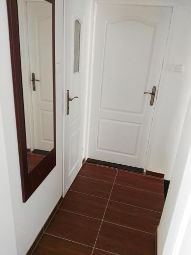 a hallway with white doors and a mirror at Leipa Apart in Česká Lípa