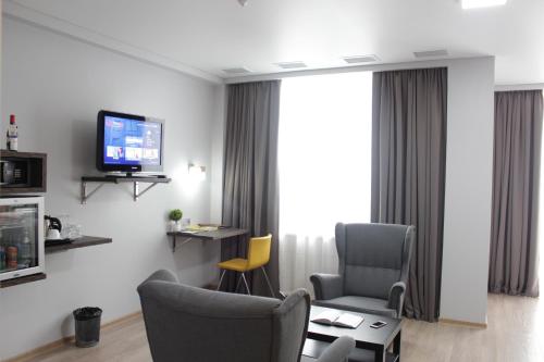 a living room with two chairs and a tv at Smart Hotel Bishkek in Bishkek