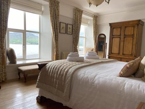a bedroom with a large white bed with windows at Dolly's Cottage in Warrenpoint