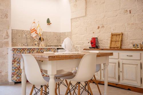 a kitchen with a table and white chairs at Arcueve Casa Vacanze in Ceglie Messapica
