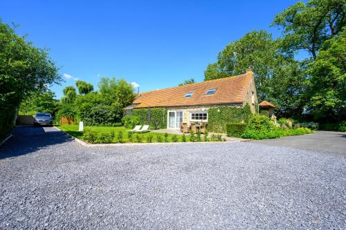 a house with a gravel driveway in front of it at De Scheure, charmant vakantiehuisje midden in de natuur in Alveringem