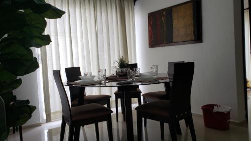 a dining room table with chairs and a table with glasses at Departamento equipado a unos pasos de la playa, 2 Recamaras Aire acondicionado in Manzanillo