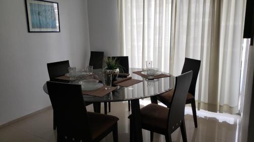 a dining room table with chairs and a glass tableablish at Departamento equipado a unos pasos de la playa, 2 Recamaras Aire acondicionado in Manzanillo