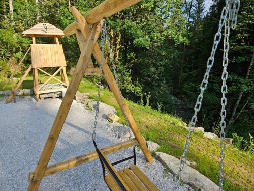 a swing yard with a swing tower and a tree at POHORJE HOUSE 2 FOUR APPARTMETNS in Oplotnica