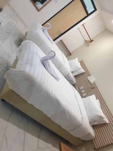 ein Bett mit weißen Laken und Kissen in einem Zimmer in der Unterkunft La bianca Home in Kota