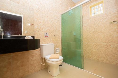 une salle de bain avec toilettes et douche en verre dans l'établissement Rancho Colonial 6 suítes acesso ao Lago das Brisas, à Corumbazul