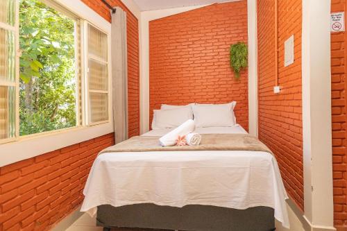 un lit dans une chambre avec un mur de briques dans l'établissement Rancho Colonial 6 suítes acesso ao Lago das Brisas, à Corumbazul