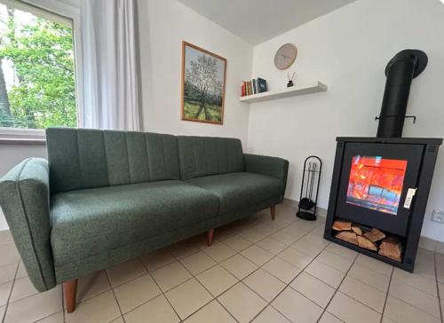 a green couch in a living room with a fireplace at Cosy cottage with wellness in Mirošovice
