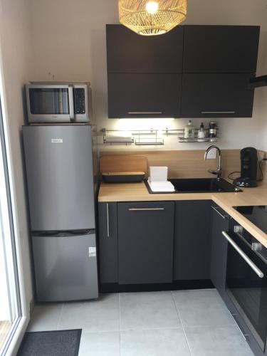 une cuisine avec un réfrigérateur et un micro-ondes dans l'établissement LouEva, à Mimizan