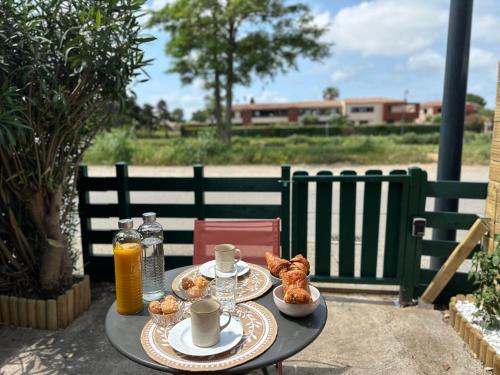 une table avec deux assiettes de nourriture et de jus d'orange dans l'établissement Magnifique studio Le FLAMANT DORE avec Loggia, Terrasse & Climatisation, Proche Mer, à Aigues-Mortes