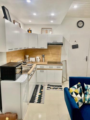 une cuisine avec des placards blancs et un canapé bleu dans l'établissement Isaiah House cosy Garden, à Deuil-la-Barre
