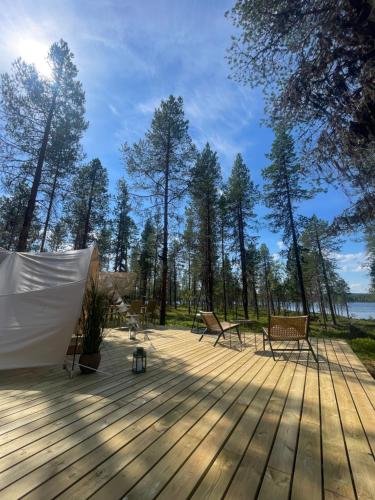 a wooden deck with two benches and a tent at LaplandLiv Glampingtent with private sauna at the lake! in Björkliden