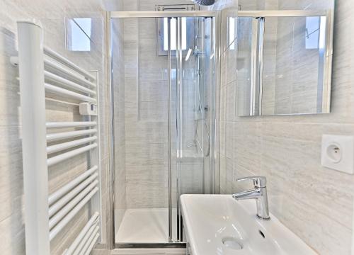 une salle de bain blanche avec une douche et un lavabo dans l'établissement Magnifique et spacieux appartement proche Paris, à Puteaux