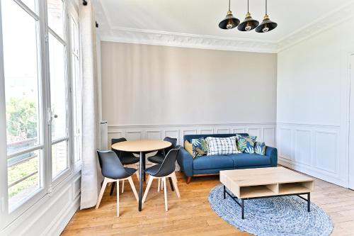 un salon avec un canapé bleu et une table dans l'établissement Magnifique et spacieux appartement proche Paris, à Puteaux