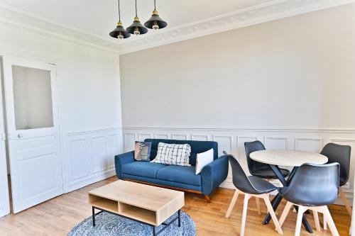 un salon avec un canapé bleu et une table dans l'établissement Appartement lumineux Banlieue Parisienne - Puteaux, à Puteaux