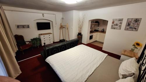a bedroom with a white bed and a kitchen at Leipa Apart in Česká Lípa