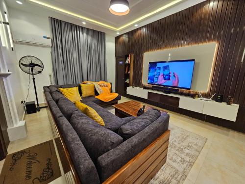 a living room with a large couch and a flat screen tv at Atlantic Experiences, Garki, Abuja in Abuja