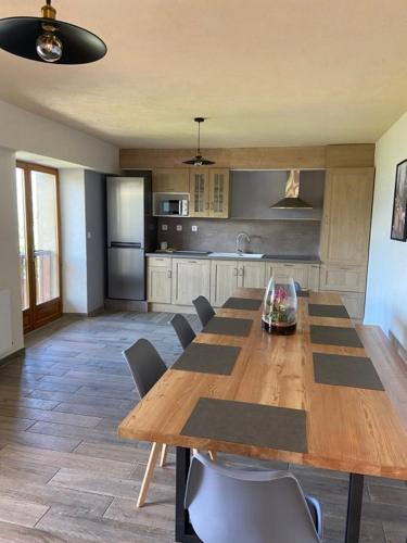 une cuisine avec une grande table et des chaises en bois dans l'établissement La Grange - Camping le Mont Orel, à Saint-André-dʼEmbrun