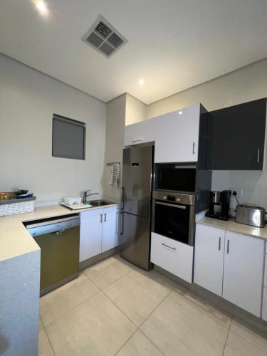 a kitchen with white cabinets and stainless steel appliances at Low Tide in Densainagar